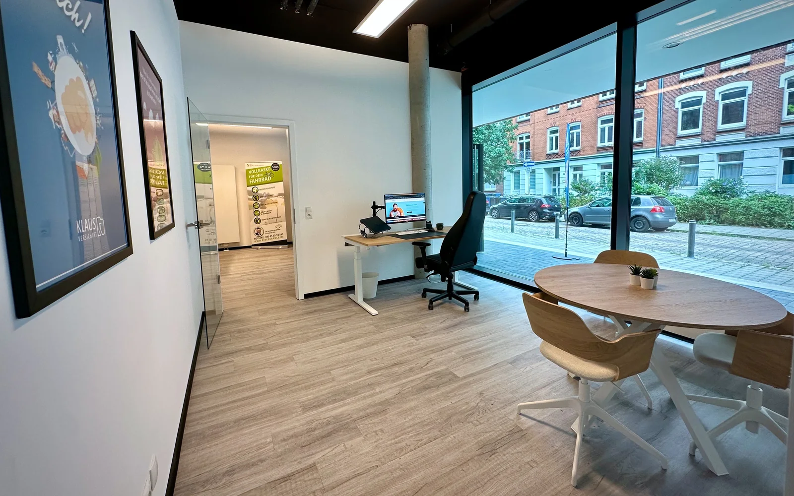 Blick in unser helles Kieler Büro mit Arbeitsplatz, Besprechungstisch und großer Fensterfront zur Straße